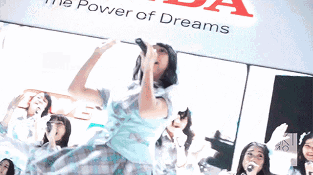 a girl singing in front of a sign that says the power of dreams