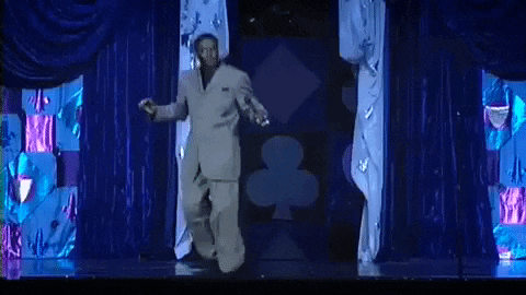 a man in a suit is dancing on a stage