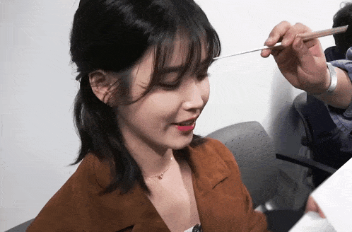 a woman in a brown jacket is being painted with a brush