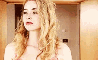 a woman with blonde hair and freckles is standing in front of a mirror in a room .