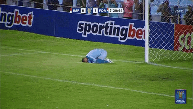 a soccer player kneeling on the field in front of a sportingbet sign
