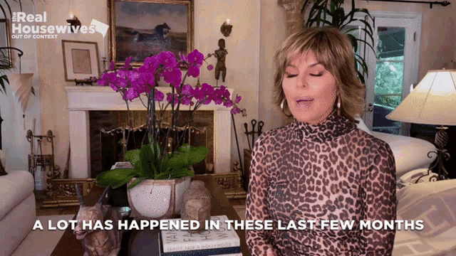 a woman in a leopard print top says " a lot has happened in these last few months " in front of a fireplace