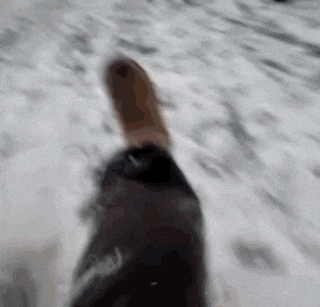 a person 's foot is walking through the snow with a black jacket on