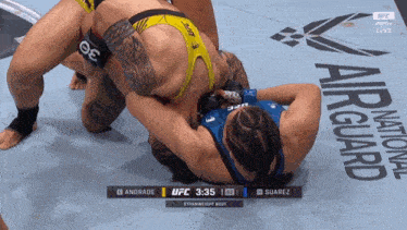 two women are wrestling on a mat that says air guard on it