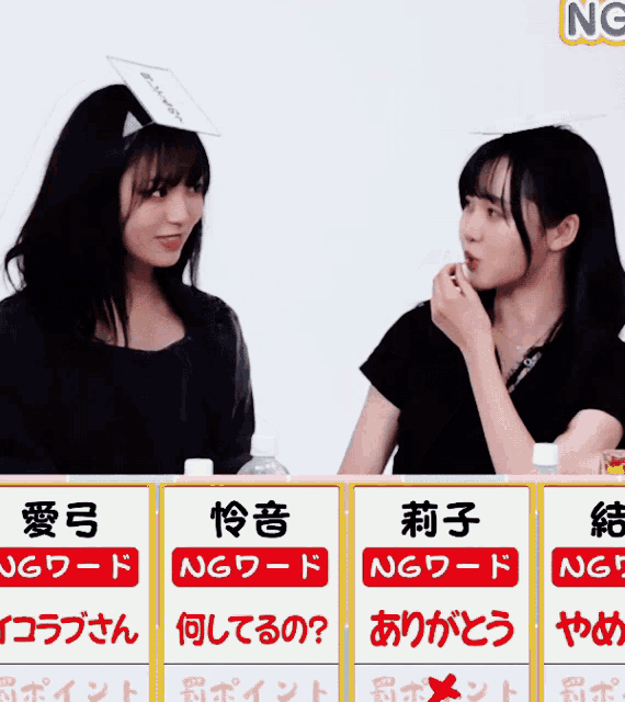two women are sitting at a table with a sign that says ng on it