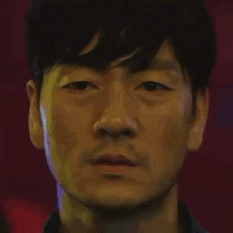 a close up of a man 's face with a beard looking at the camera with a red background .