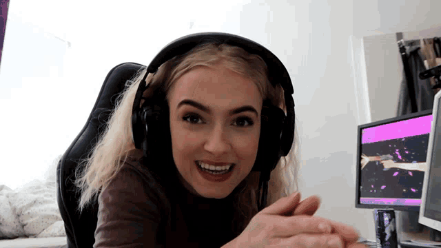 a woman wearing headphones is smiling in front of a computer