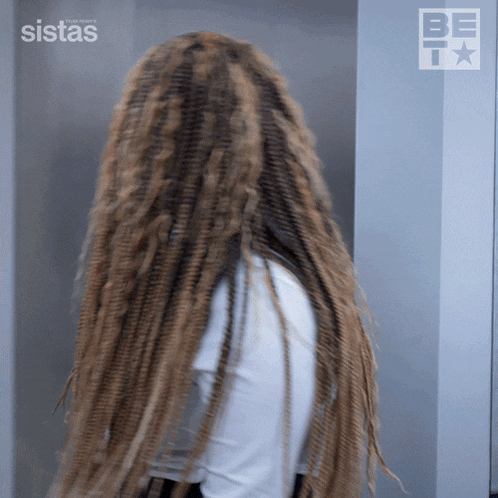 a woman with dreadlocks is standing in front of a sign that says ' sistas ' on it