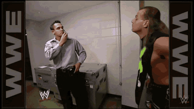 two men are standing next to each other in a room with wwe written on the bottom