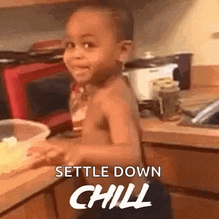 a shirtless little boy is standing in a kitchen preparing food and smiling .