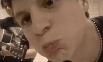 a close up of a person making a funny face while holding a guitar in a room .