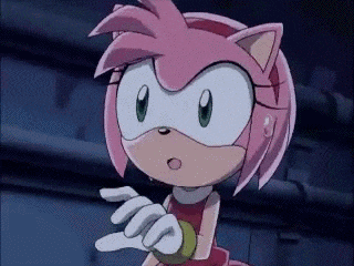 amy rose from sonic the hedgehog is standing in a dark room with her hands out .
