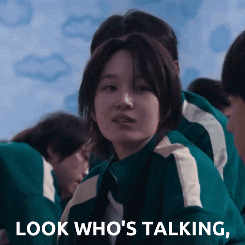 a girl in a green jacket with the words look who 's talking below her