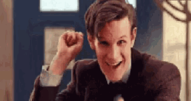 a man in a suit and tie is smiling and holding his fist up in the air .
