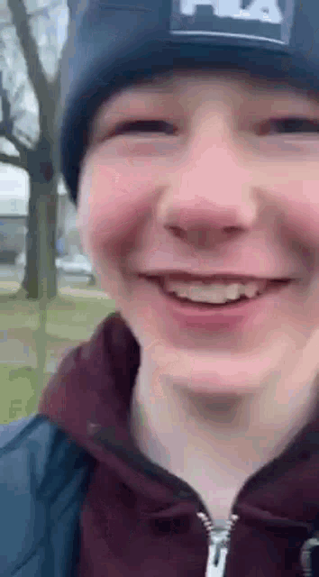 a young man wearing a beanie and a hoodie is smiling .