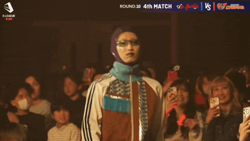 a man in a hooded jacket is standing in front of a crowd with the number 23 on his shirt