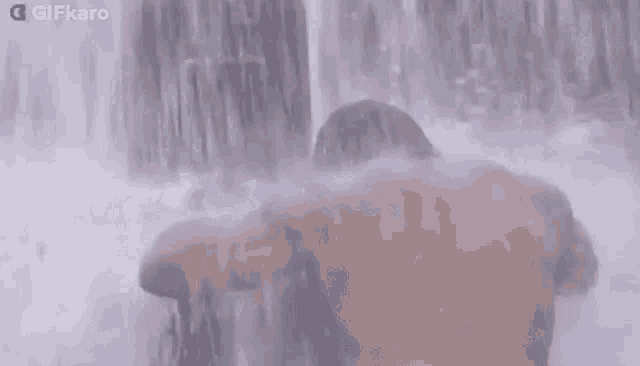 a man is standing in front of a waterfall with his head in the water .