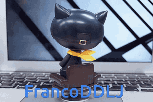 a black cat figurine sits on a laptop keyboard with francoddlj written in blue