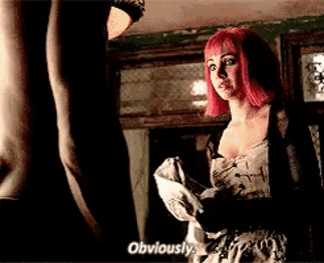a woman with pink hair is standing next to a man and saying obviously