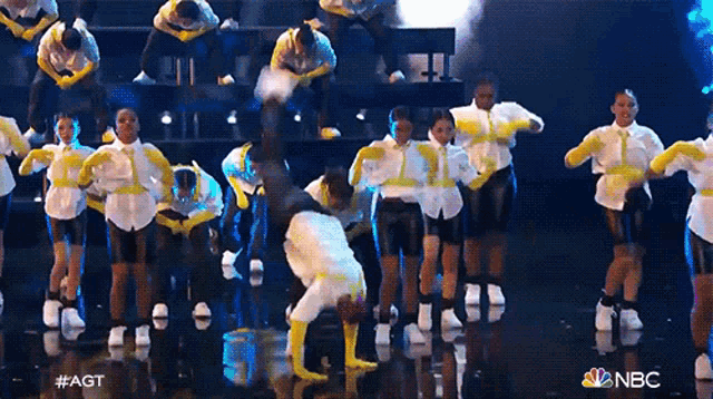 a group of dancers are performing on a stage with the nbc logo in the background