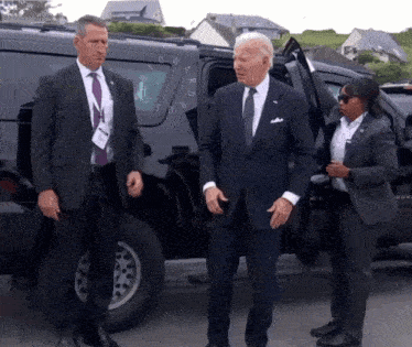a man in a suit and tie is standing next to a woman in a suit and tie