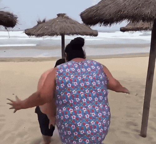 a man and a woman are standing on a beach with umbrellas