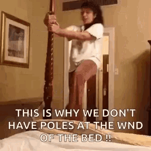 a woman is standing on top of a bed with a pole in her hand .