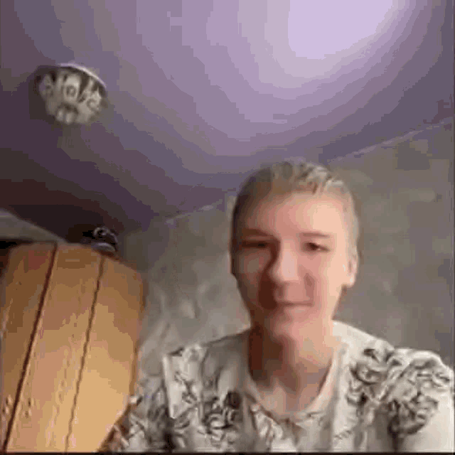 a young man is sitting in a room with a purple ceiling and a lamp on it .