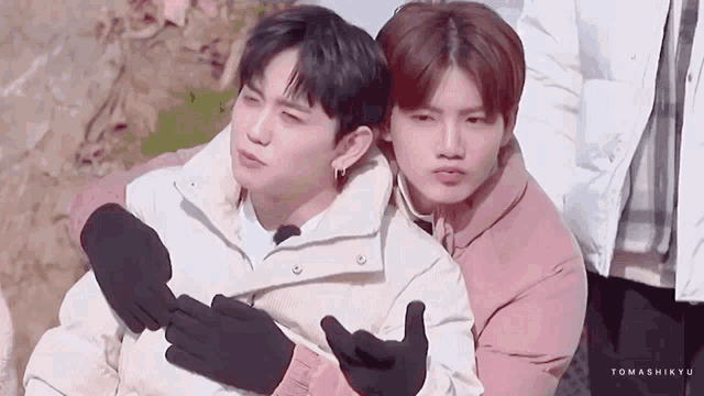 two young men are hugging each other and one of them is wearing gloves .