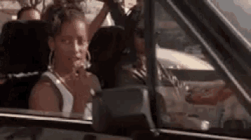 a woman is sitting in a car smoking a cigarette .