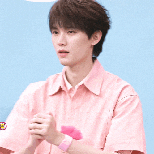 a young man in a pink shirt has a pink wristband on