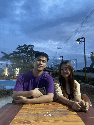 a man in a purple shirt sits next to a woman in a white shirt with the word believe on it