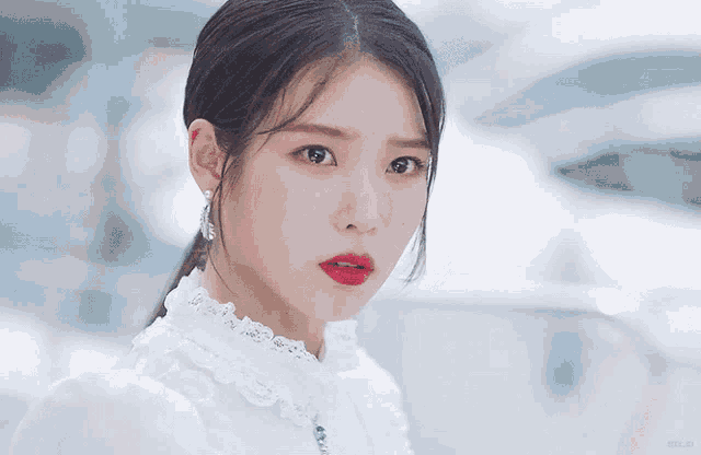 a close up of a woman 's face wearing a white dress and red lipstick