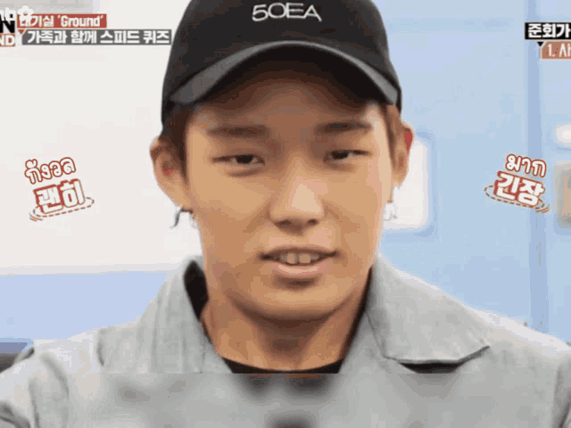 a man wearing a black 50ea hat looks at the camera