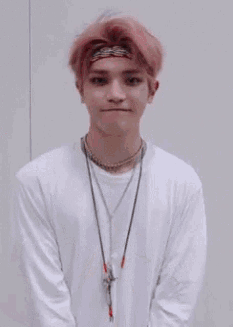 a young man with pink hair is wearing a white shirt and a headband and holding a jacket .