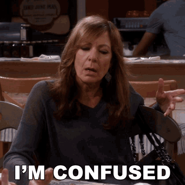 a woman sitting at a table with the words i 'm confused written on her face