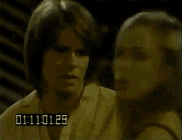 a man and a woman are standing next to each other and the time is 01 : 11 02 13