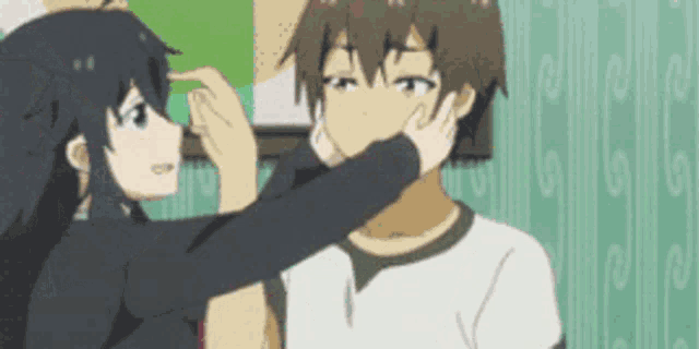 a girl is putting her hand on a boy 's face in a cartoon .