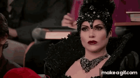a woman in a black costume is sitting in a classroom with make a gif.com in the lower right corner