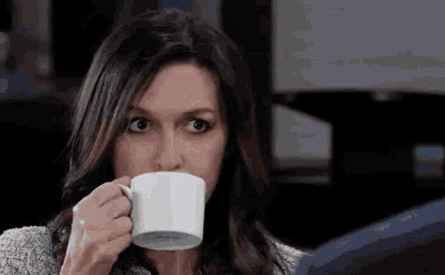a woman is drinking a cup of coffee .