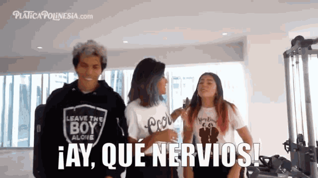 a man wearing a leave the boy alone shirt stands next to two women