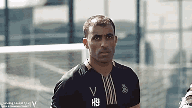 a man wearing a black and gold shirt with the letter v on it