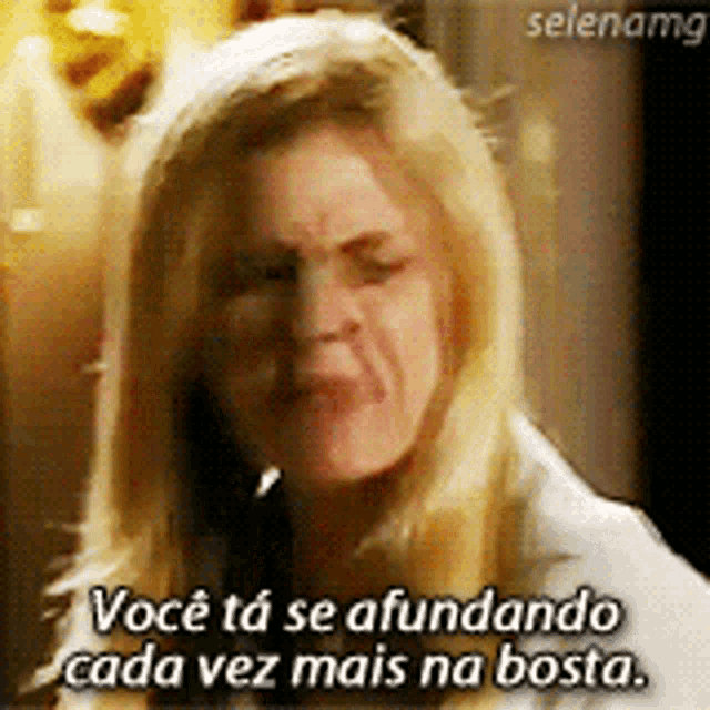 a woman with blonde hair is making a funny face and says voce ta se afundando cada vez mais na bosta