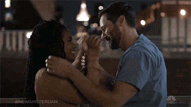 a man and a woman are kissing in front of a nbc logo