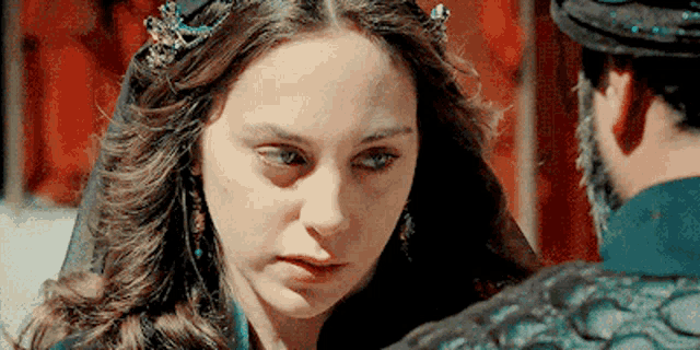 a woman with a crown on her head is looking at a man in a hat .
