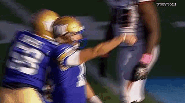 two football players are standing next to each other on a field .
