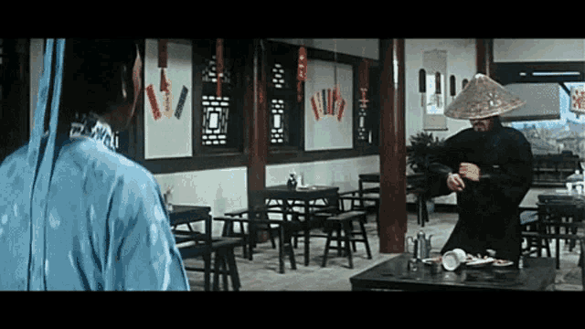 a man in a hat is standing in a room with tables and chairs