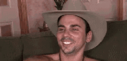 a man without a shirt is wearing a cowboy hat and making a funny face .