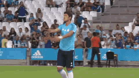 a soccer player stands on a field in front of a sign that says adidas