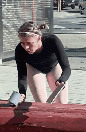 a woman in a black leotard and white tights is kneeling down on the sidewalk